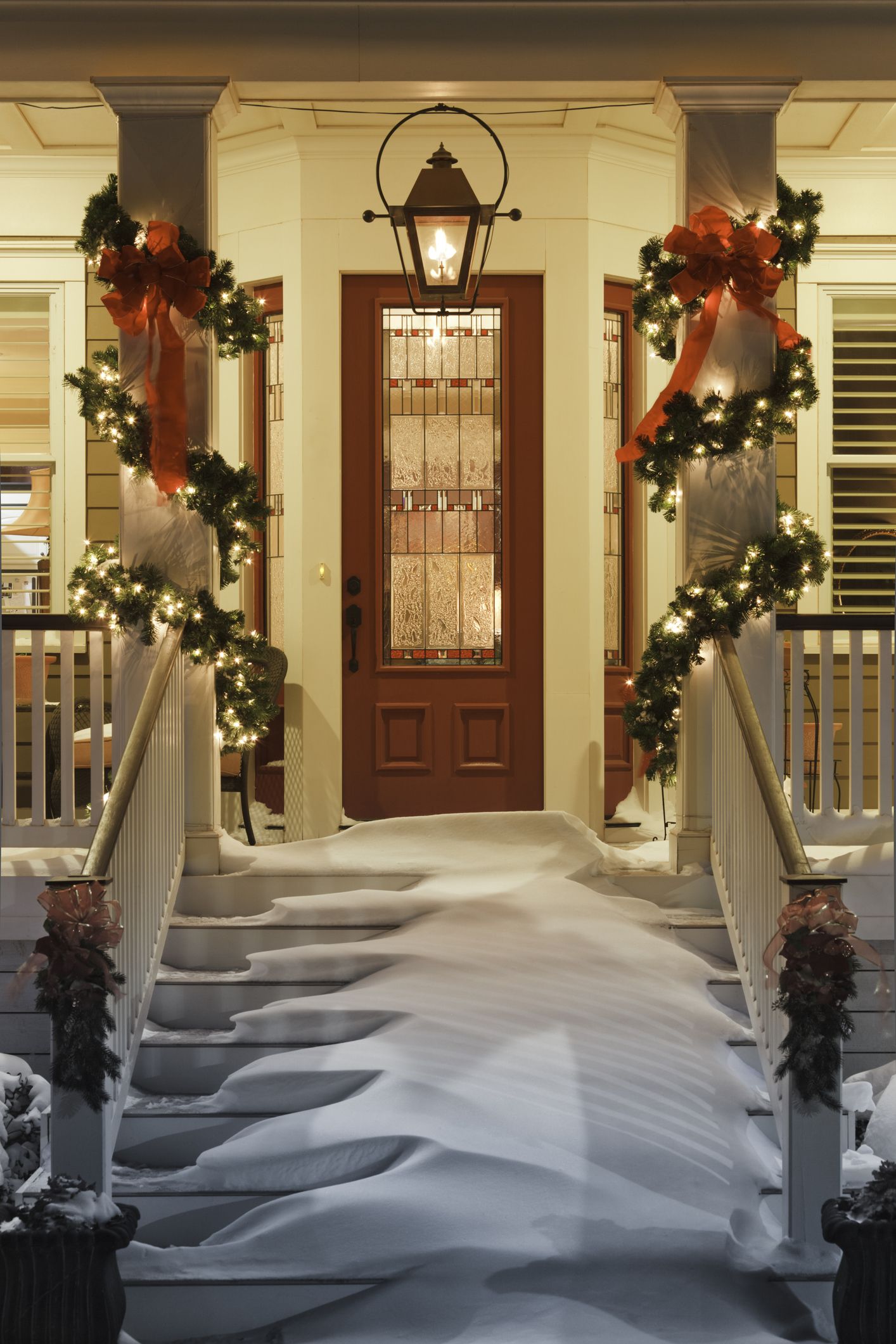 inviting christmas doorway with snow on porch stairs and railing